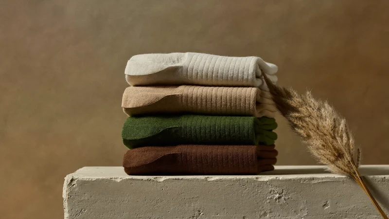 Pile de chaussettes en coton biologique mousse, argile et sable près d'une herbe séchée